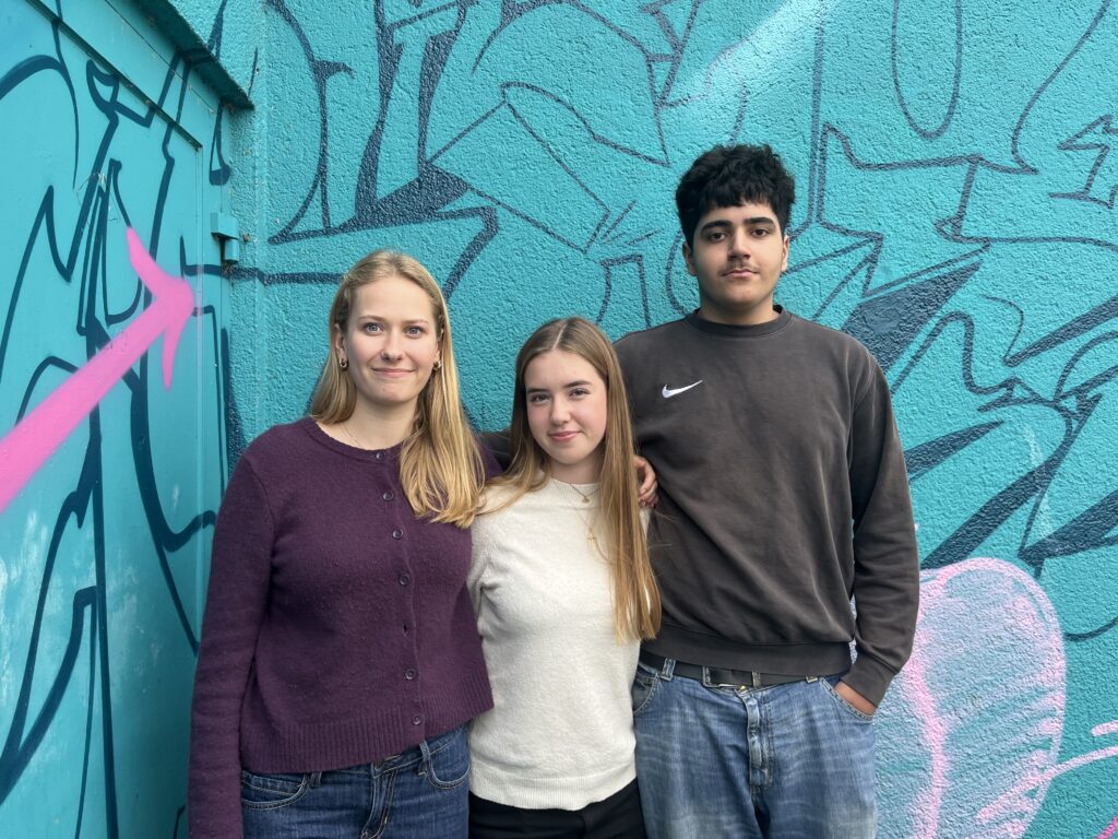 Foto der derzeitigen Schülersprecher*innen des HGK vor einer Betonwand mit Graffiti